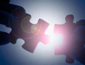 light glares down between two opposing puzzle pieces